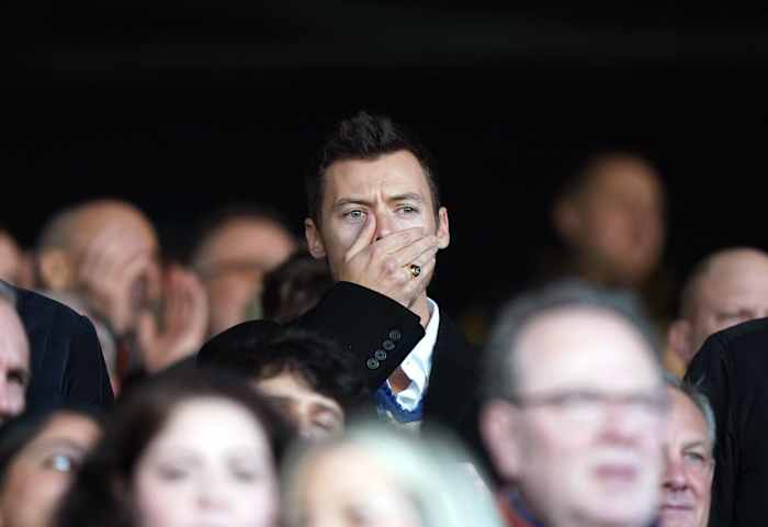 Harry Styles pictured covering his mouth with his hand while watching the Premier League game between Luton Town and Manchester United at Kenilworth Road in February 2024